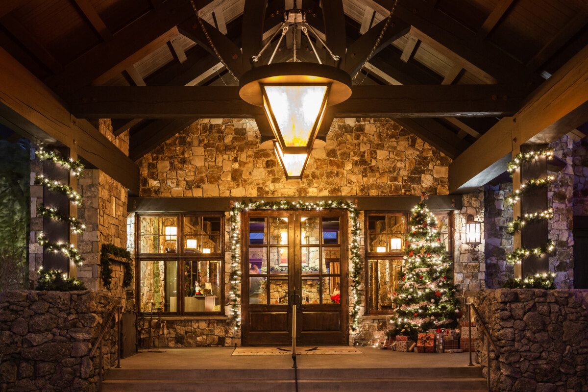 Juniper Preserve Resort entrance in Bend, Oregon decorated for the holidays with a lit Christmas tree, wrapped gifts, and garland lighting